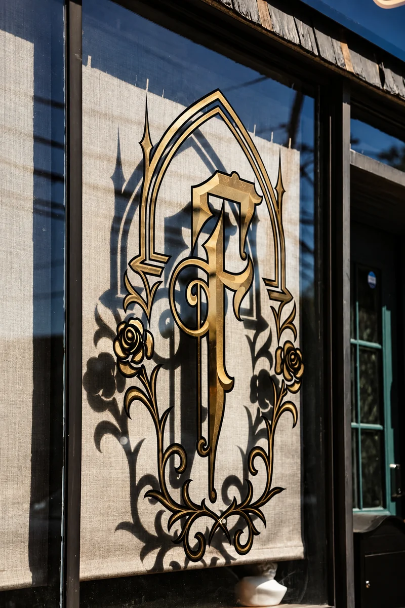 Famiglia Ink storefront with a gold-lettered sign above the green entrance door